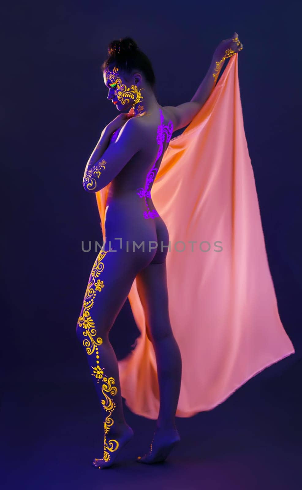 Slender model with UV makeup posing in studio, close-up
