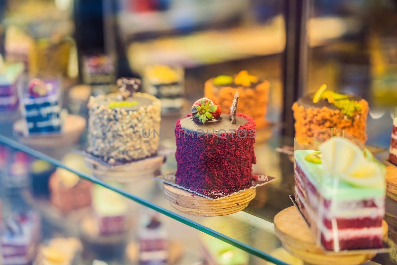 Different types of cakes in pastry shop glass display by galitskaya