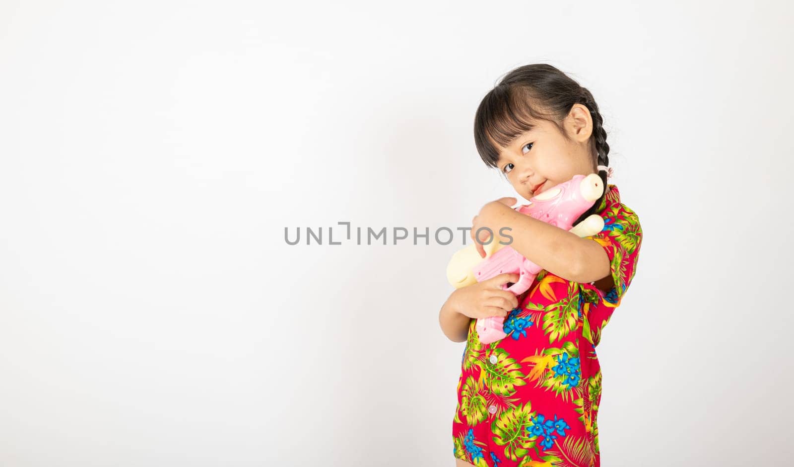 Happy Songkran Day, Asian kid girl with floral shirt hold water gun, Thai child funny hold toy water pistol and smile, isolated on white background, Thailand Songkran festival national culture concept