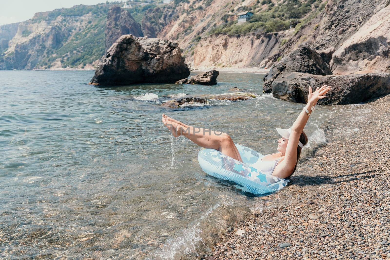 Woman summer sea. Happy woman swimming with inflatable donut on the beach in summer sunny day, surrounded by volcanic mountains. Summer vacation concept