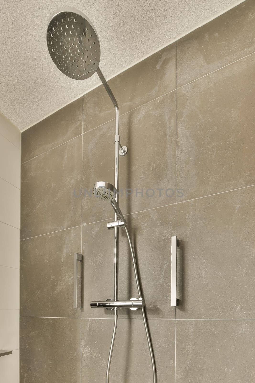 a shower in a bathroom with grey tiled walls by casamedia