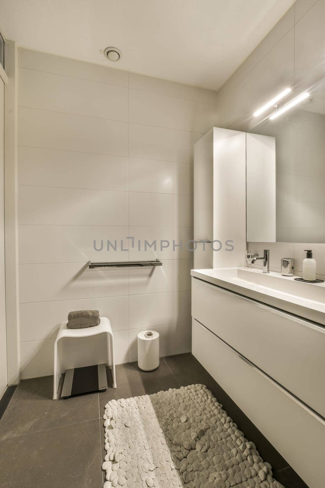 a white bathroom with a white vanity and a stool by casamedia