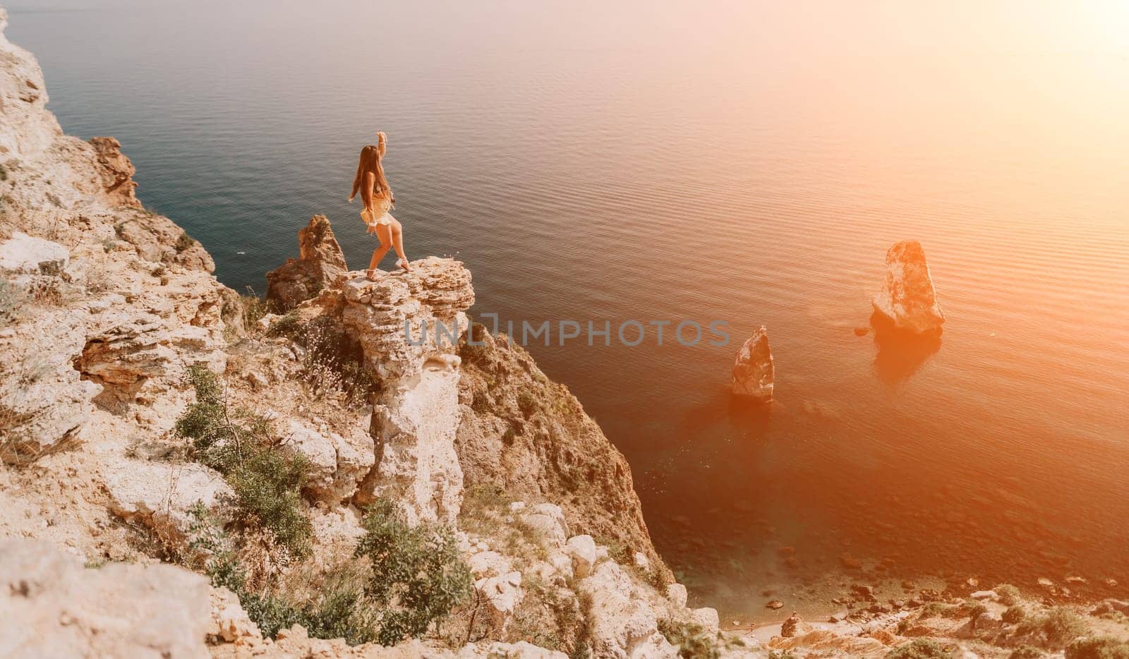 Woman travel sea. Happy tourist taking picture outdoors for memories. Woman traveler looks at the edge of the cliff on the sea bay of mountains, sharing travel adventure journey.