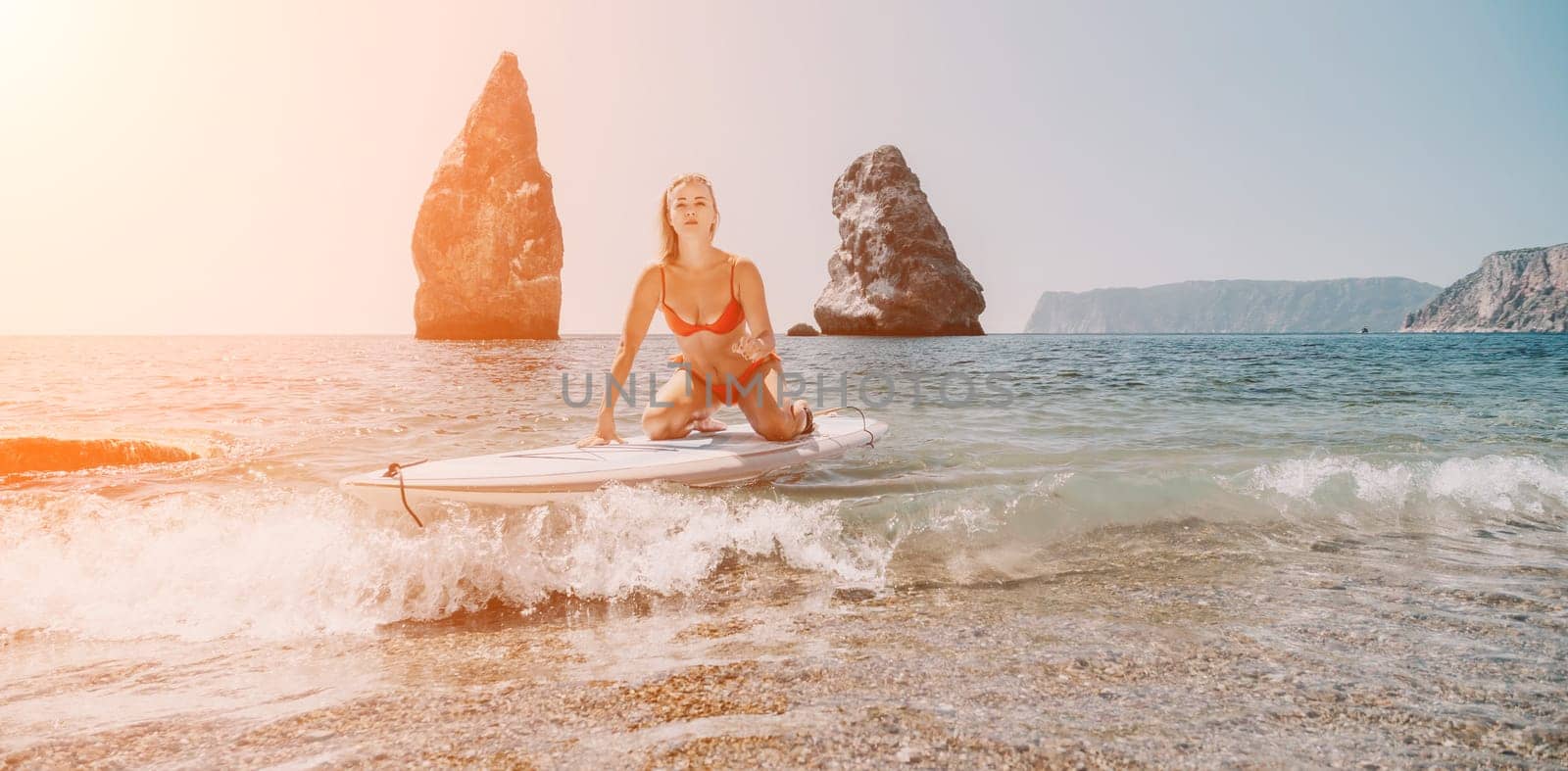 Woman sea sup. Close up portrait of happy young caucasian woman with blond hair looking at camera and smiling. Cute woman portrait in red bikini posing on sup board in the sea by panophotograph