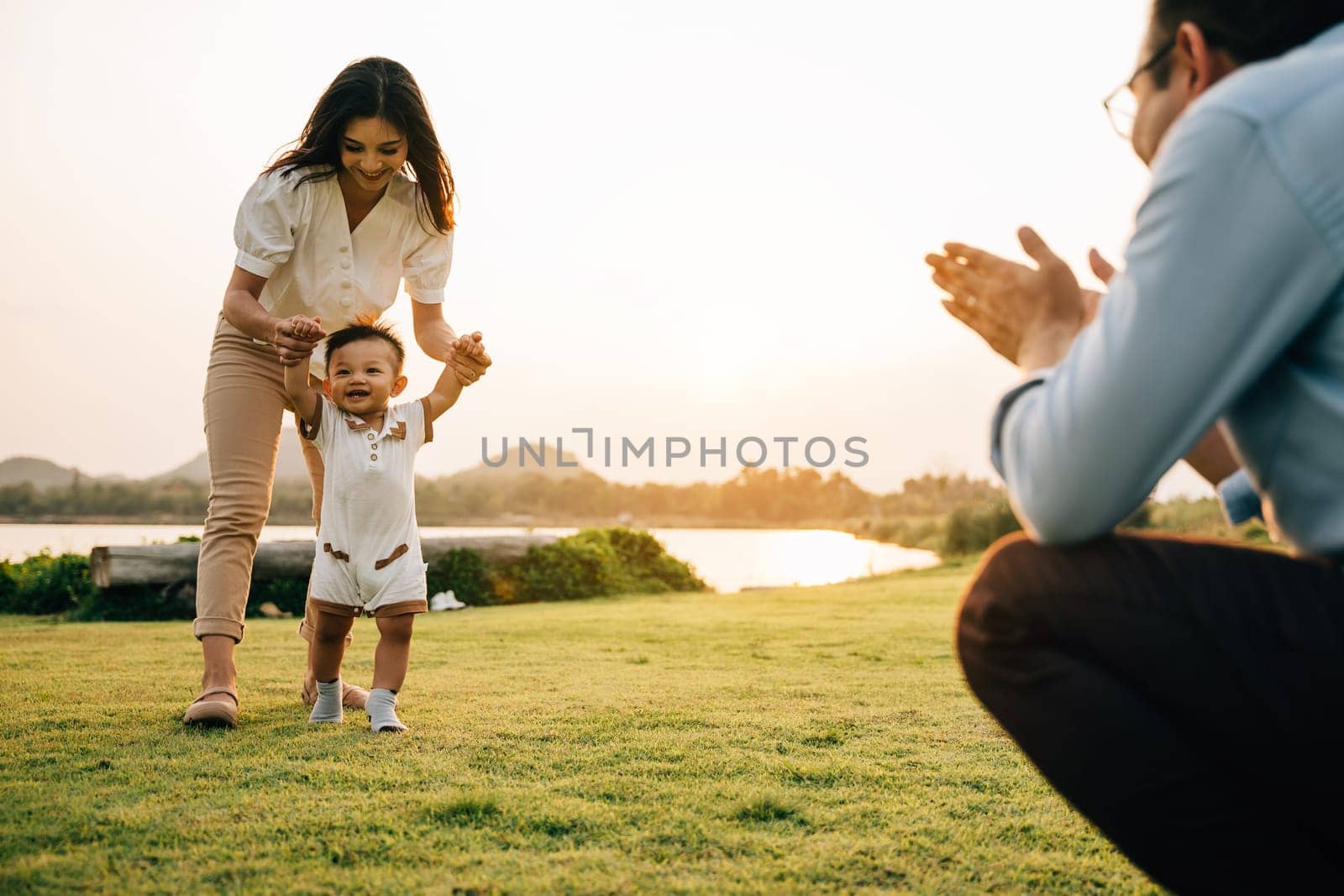 Portrait of a loving family spending quality time in nature, teaching their baby girl to walk by Sorapop