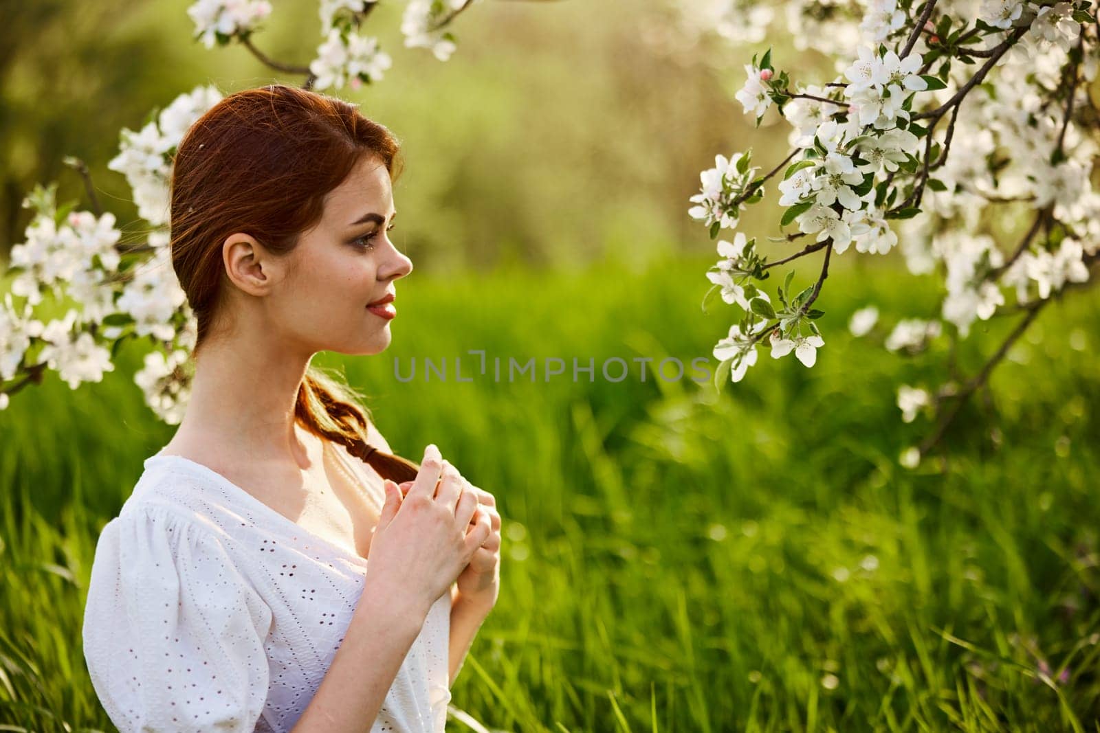 portrait of a beautiful woman looking at the flowers of an apple tree. High quality photo