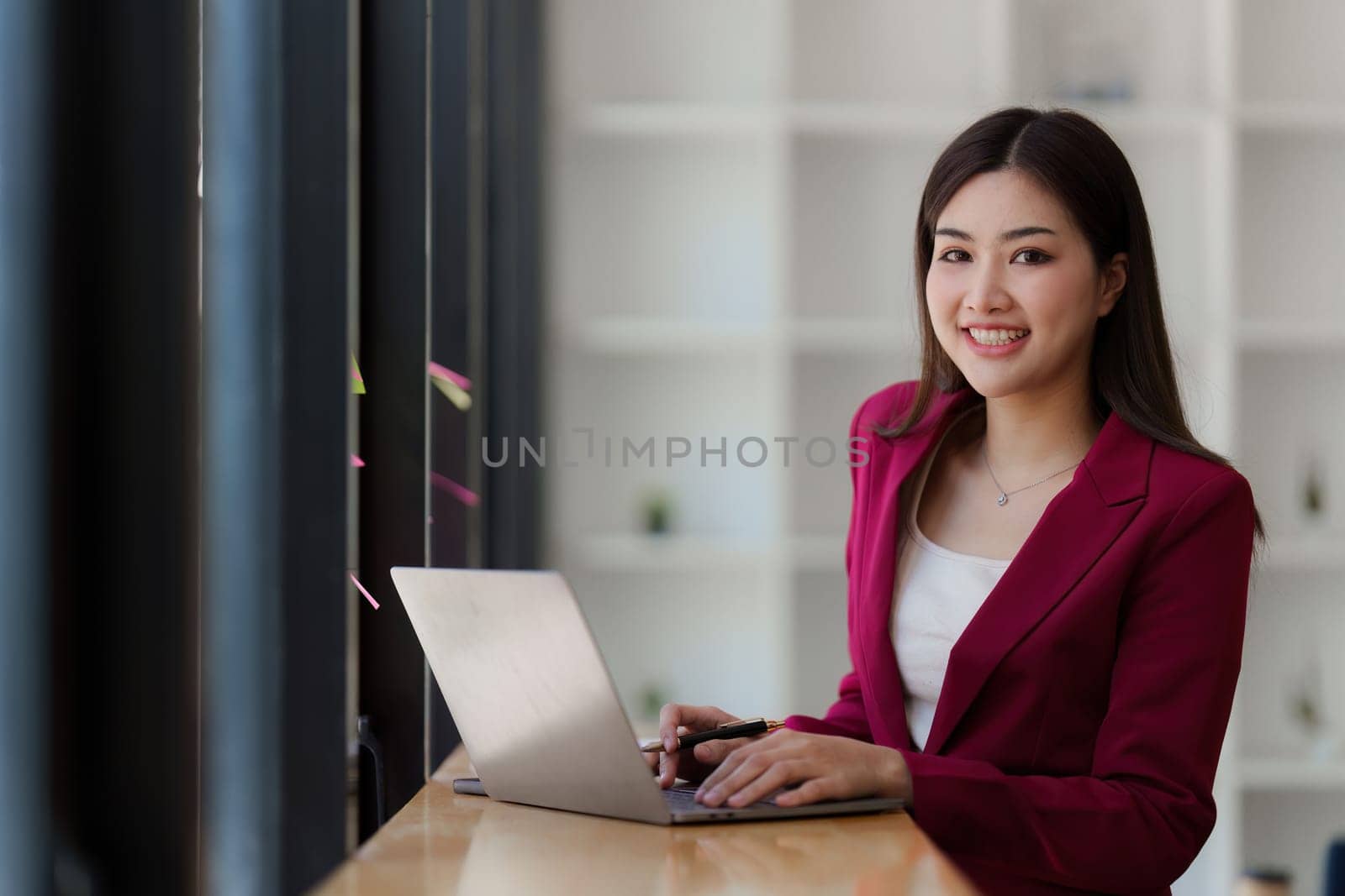 Smiling Asian Banker makes financial report and studies annual figures, analyzes profits. Accountant checks status of financial.