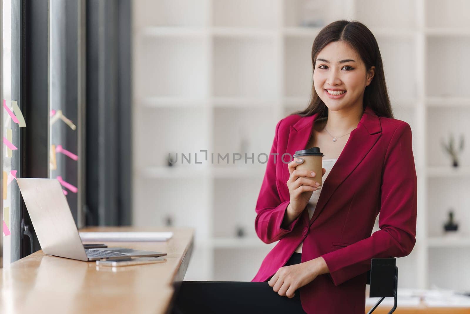 Smiling Asian Banker makes financial report and studies annual figures, analyzes profits. Accountant checks status of financial.