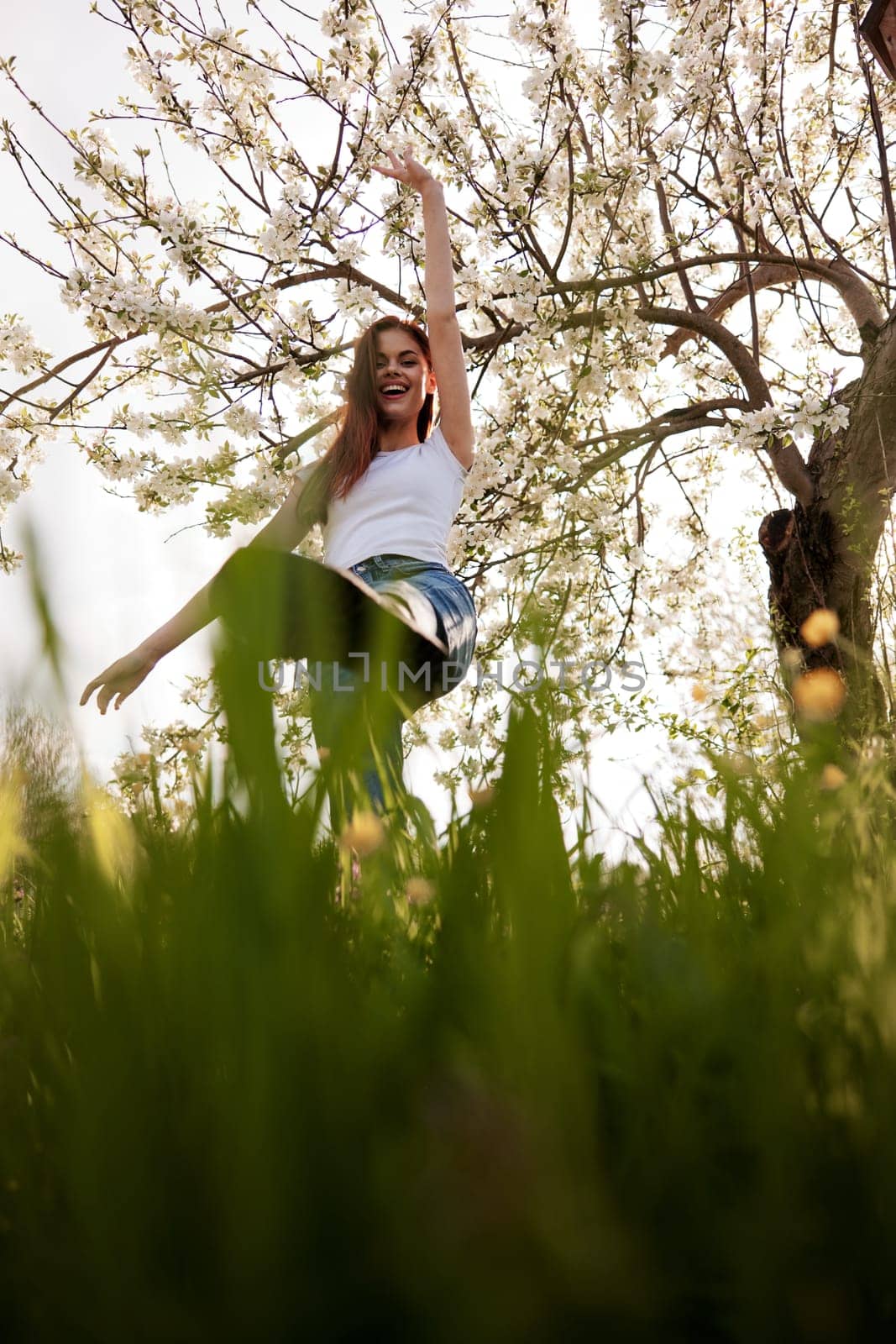 active woman posing raising her leg up against the background of a flowering tree in the park. High quality photo