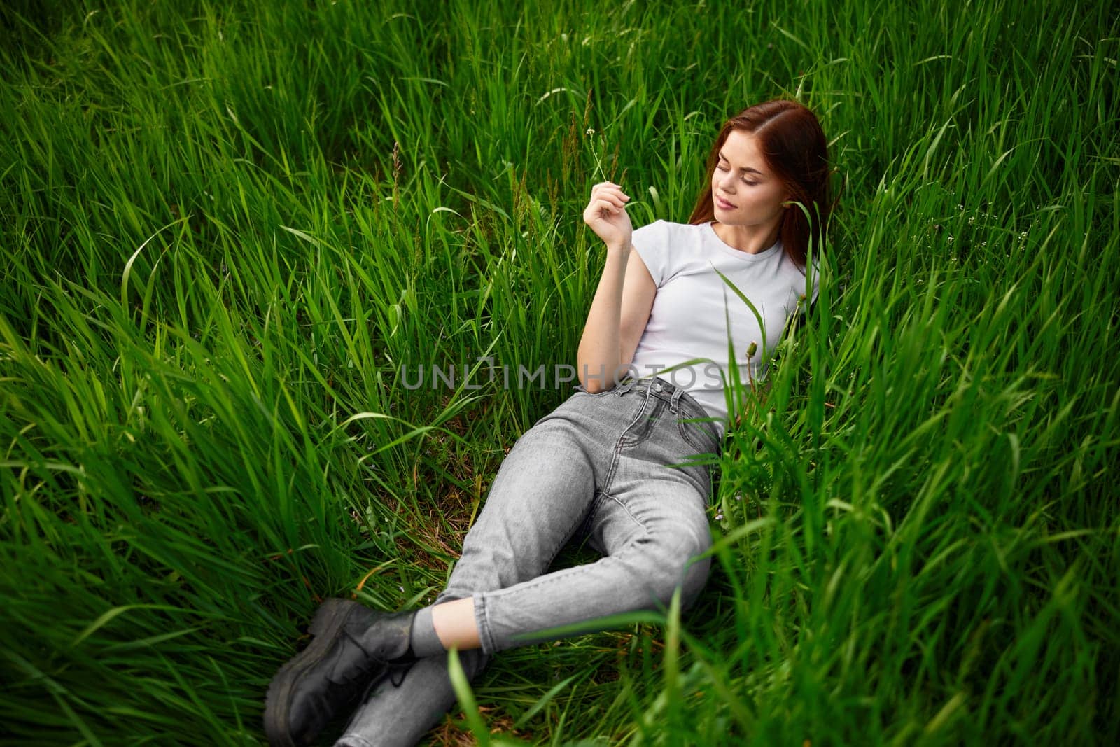 woman in gray jeans resting lying in the grass. High quality photo