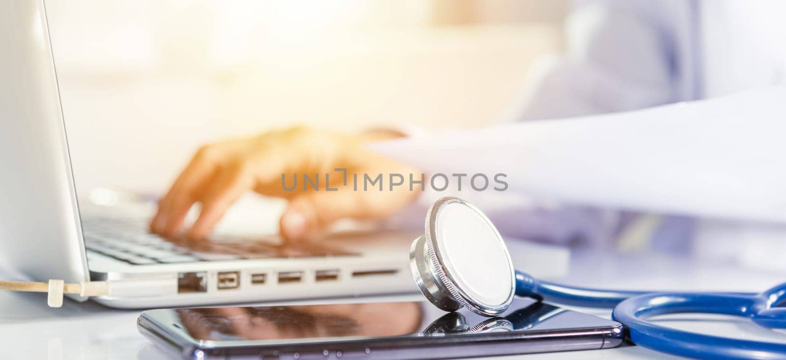 Doctor Day Concept. nurse woman in uniform with doctor stethoscope working typing information of patient prescription medical history form into laptop computer for record document data report