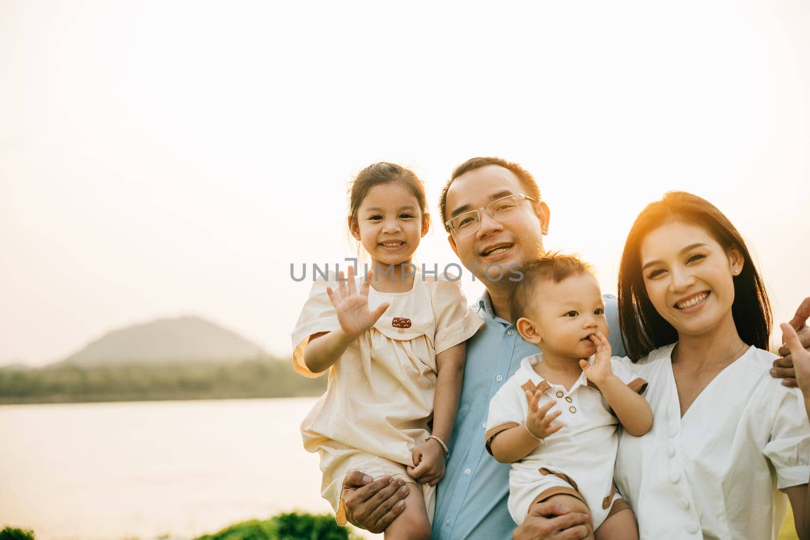 Portrait of happy family enjoying a beautiful spring day in park, with their cute baby and lovely nature surrounding them outdoor. young couple holding their adorable baby and enjoying stunning sunset
