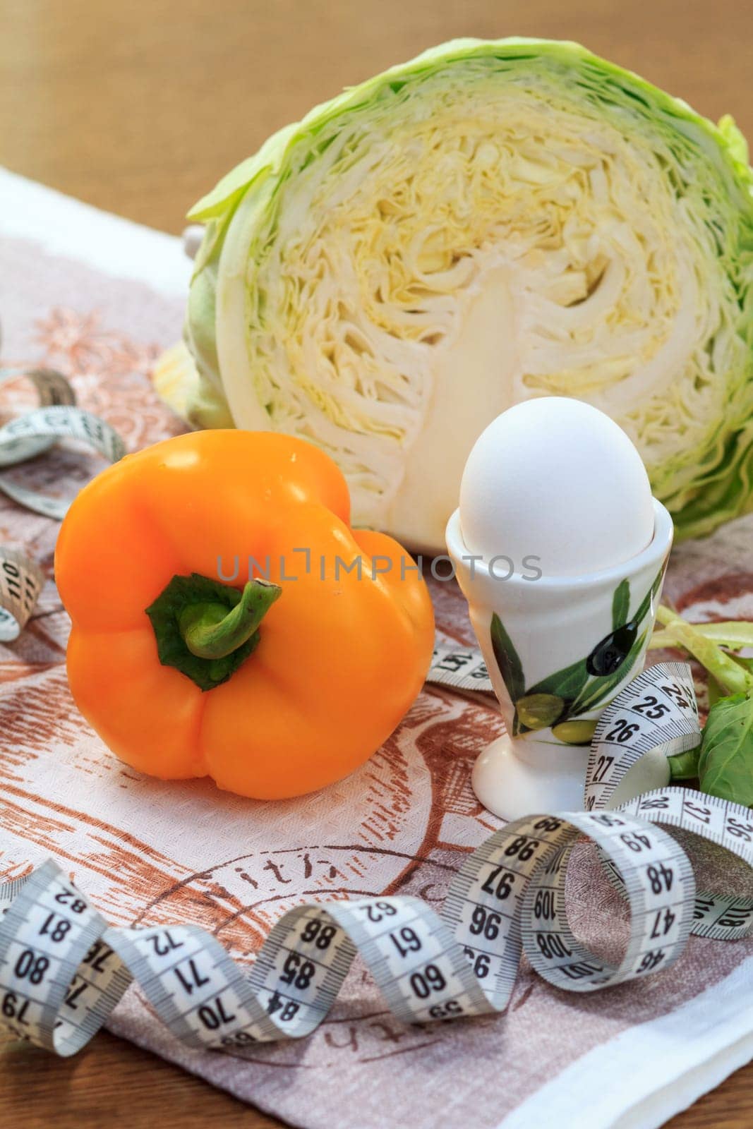 Fresh pepper, egg, cabbage, salad, ruler and multivitamin juice in glass on the table