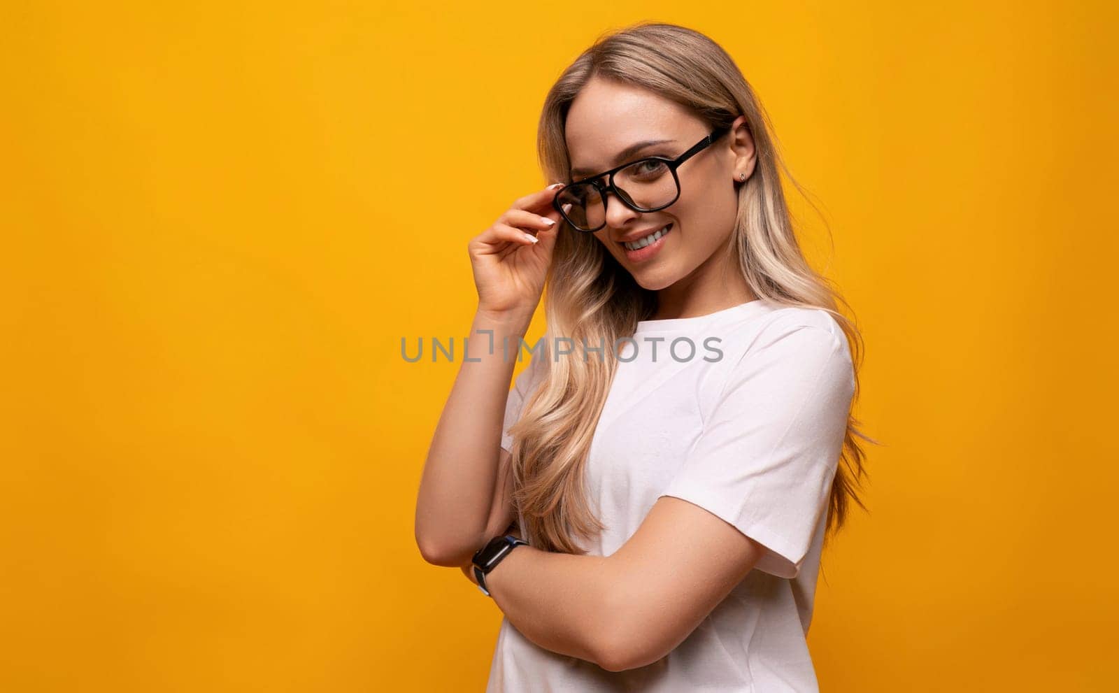 confident young woman in glasses crossed her arms in front of her on a yellow background.