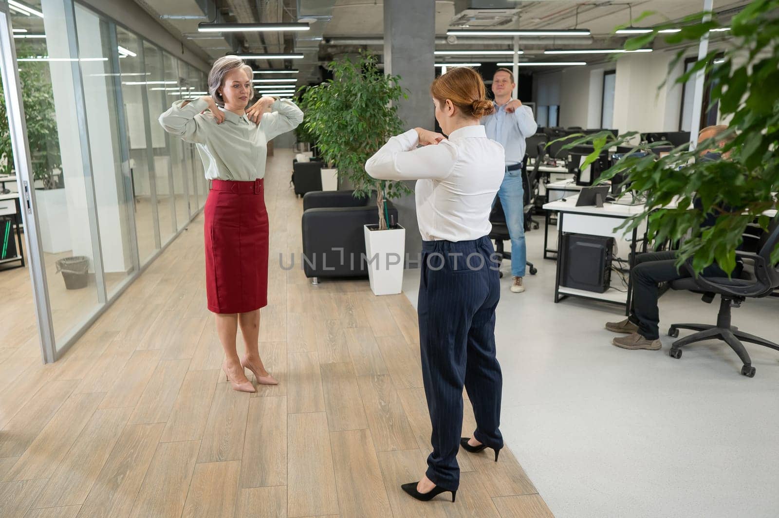 Four office workers warm up during a break. Employees do fitness exercises at the workplace