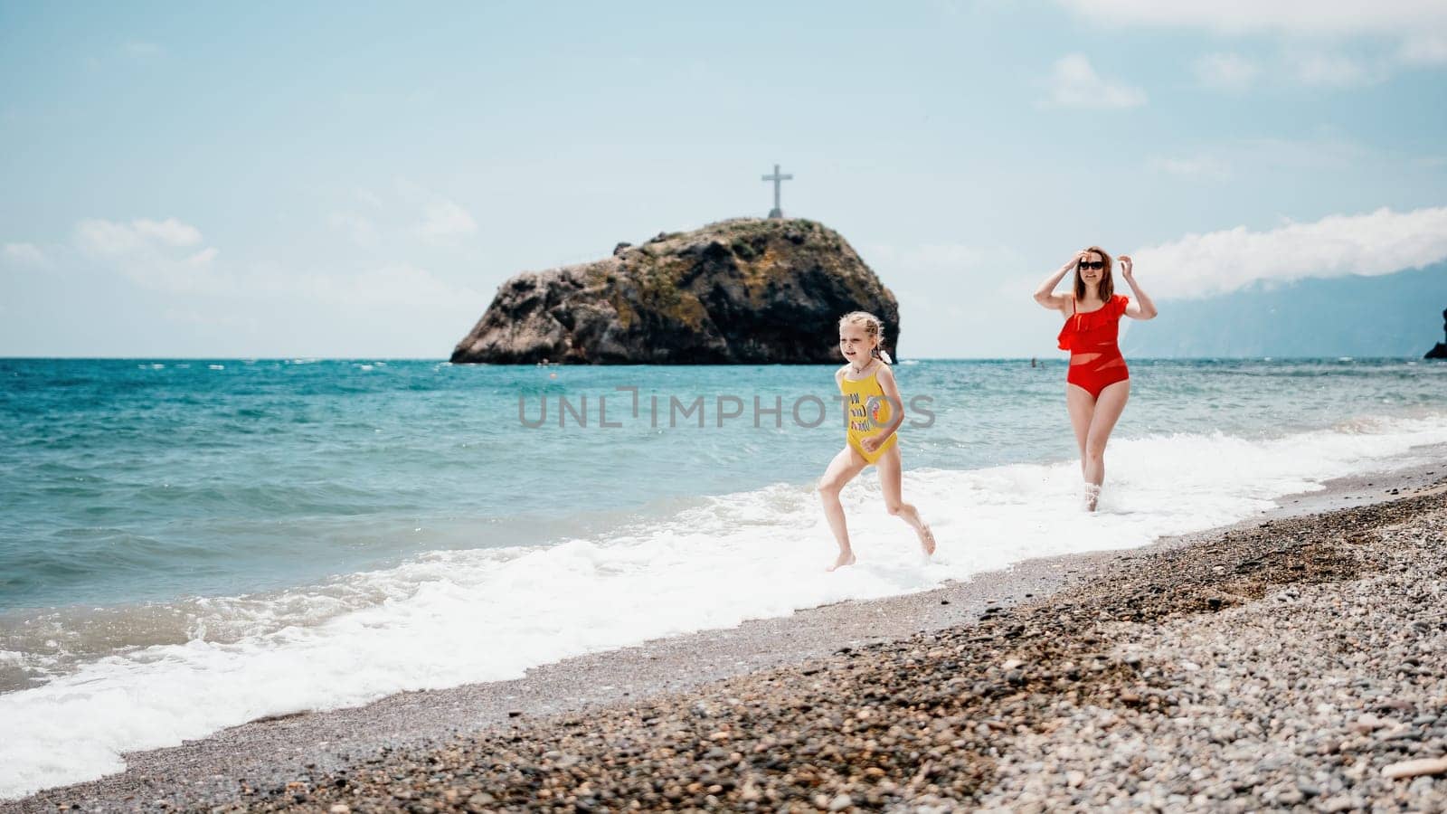 Happy loving family mother and daughter having fun together on the beach. Mum playing with her kid in holiday vacation next to the ocean - Family lifestyle and love concept.