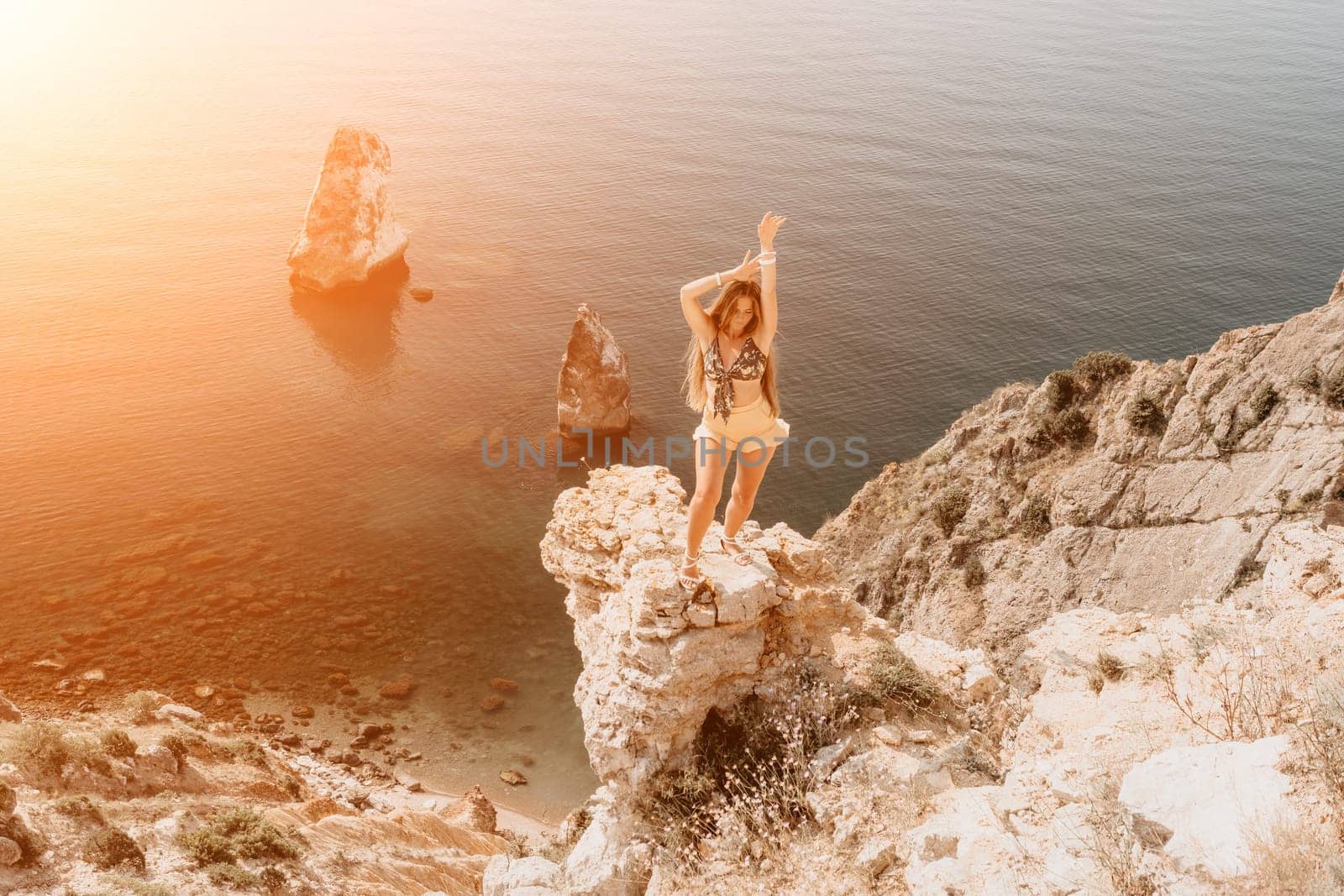 Woman travel sea. Happy tourist taking picture outdoors for memories. Woman traveler looks at the edge of the cliff on the sea bay of mountains, sharing travel adventure journey.