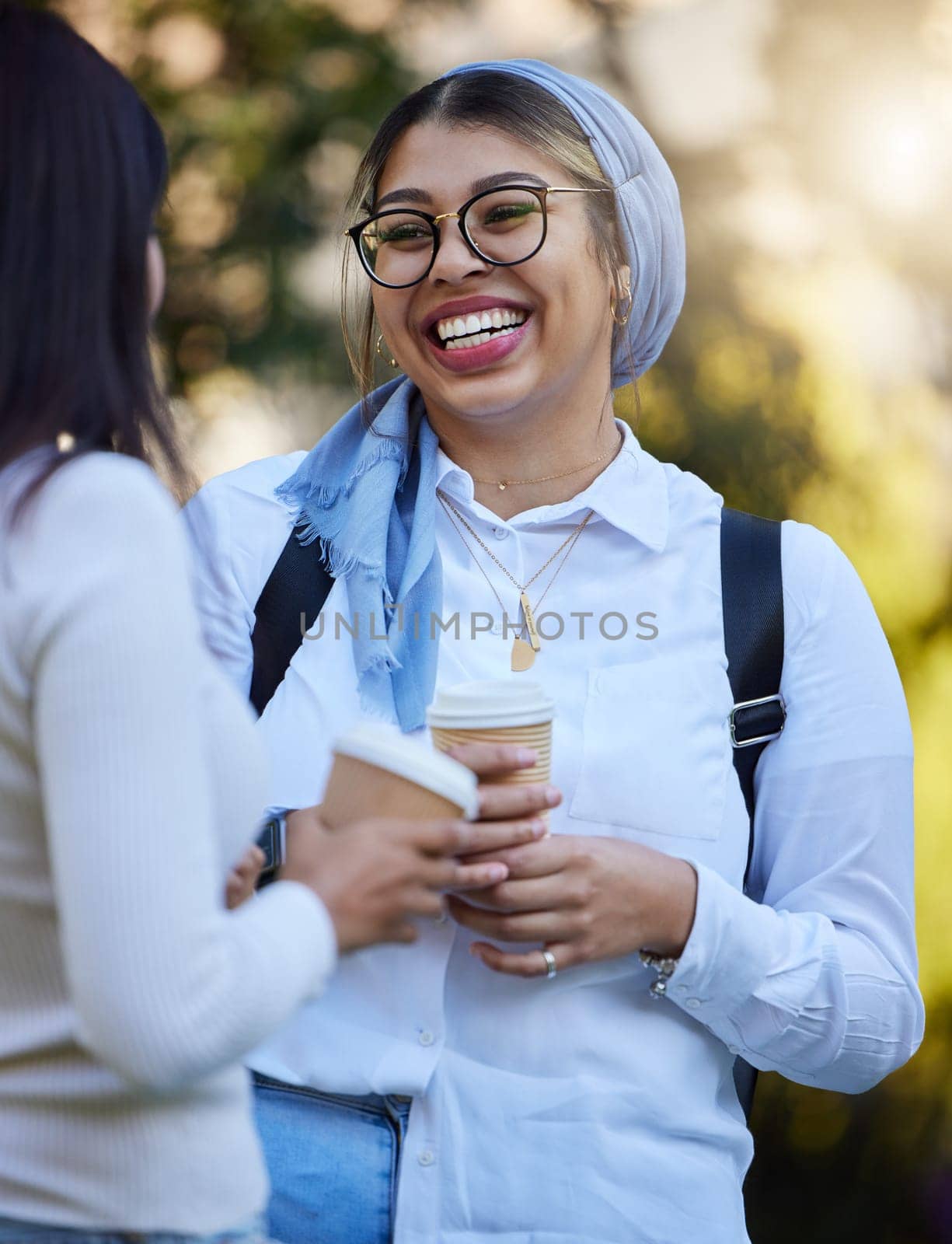 Laughing, break or university friends at park on campus for learning, education or goals together. Funny girls Muslim or students relaxing with school books meeting for research or college knowledge by YuriArcurs