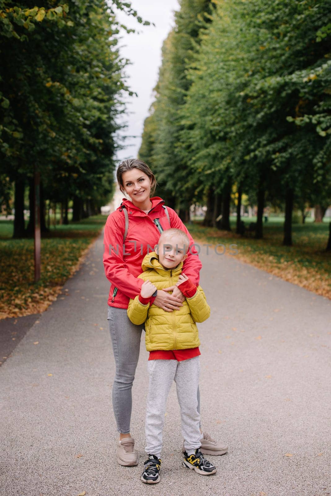 mother and son stand hugging in the park in the fall. happy mother playing with her son in the park. Mother hugs her son while standing in the forest in autumn.