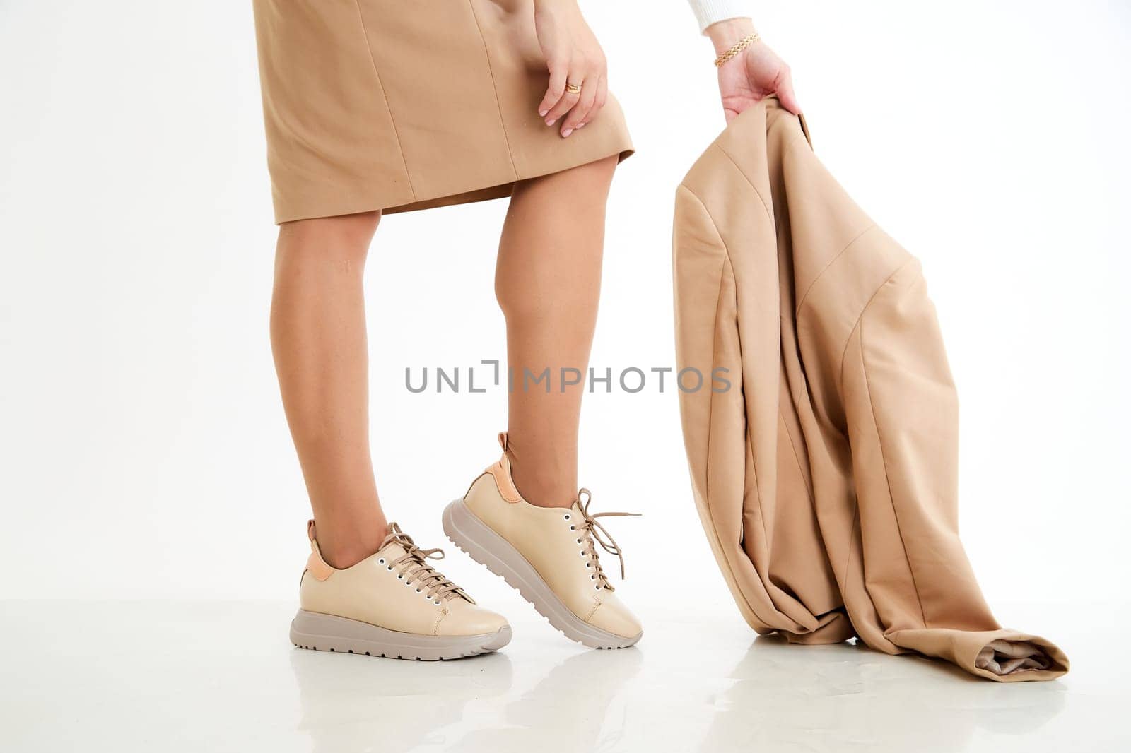 Beautiful sneakers on woman legs in studio on white background. Fashionable shooting of a young girl with beautiful legs