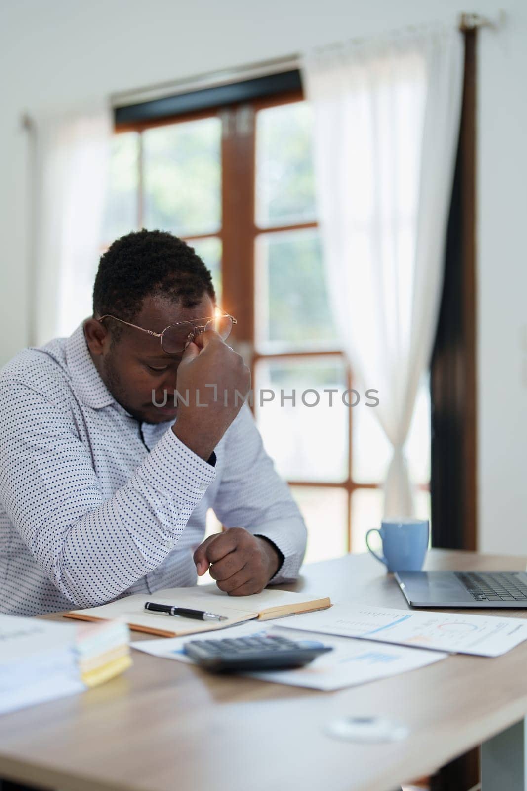 Burnout American African business man in stress works with many paperwork document, migraine attack, Freelance, work from home by Manastrong