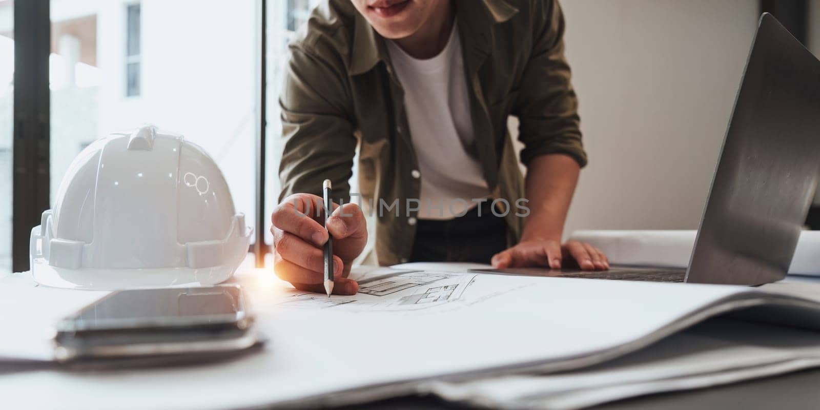Architect or Engineer working with blueprints for architectural plan, engineer sketching a construction project, green energy concept.