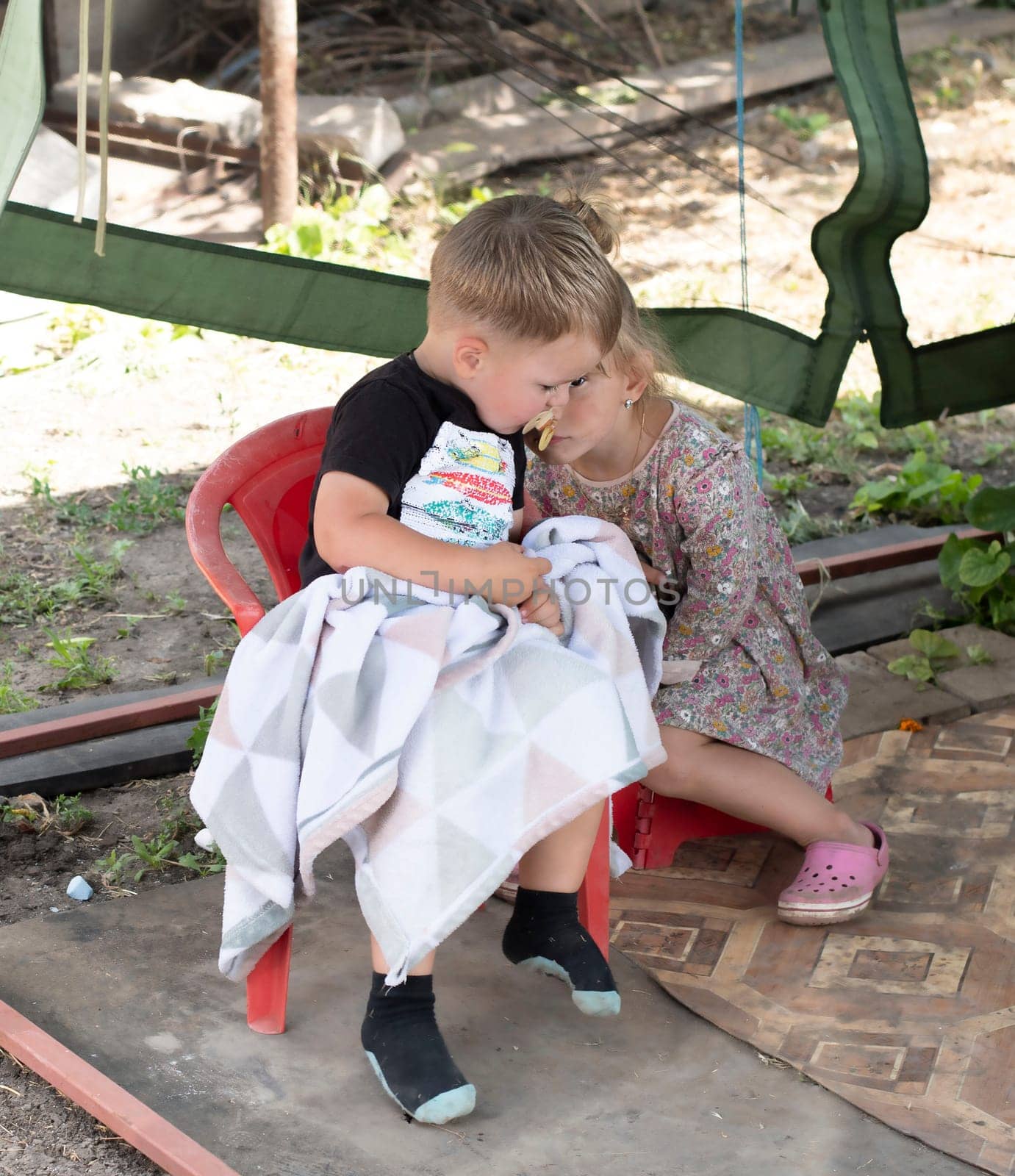 Two small children, a boy and a girl, are sitting outside at the dacha in summer. Children are smeared and dirty and soiled. by ketlit