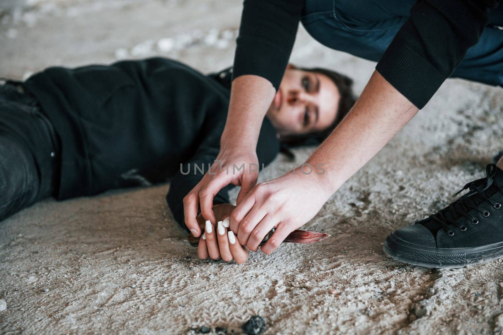 Murderer holding knife that covered in blood and sitting near his dead female young victim by Standret