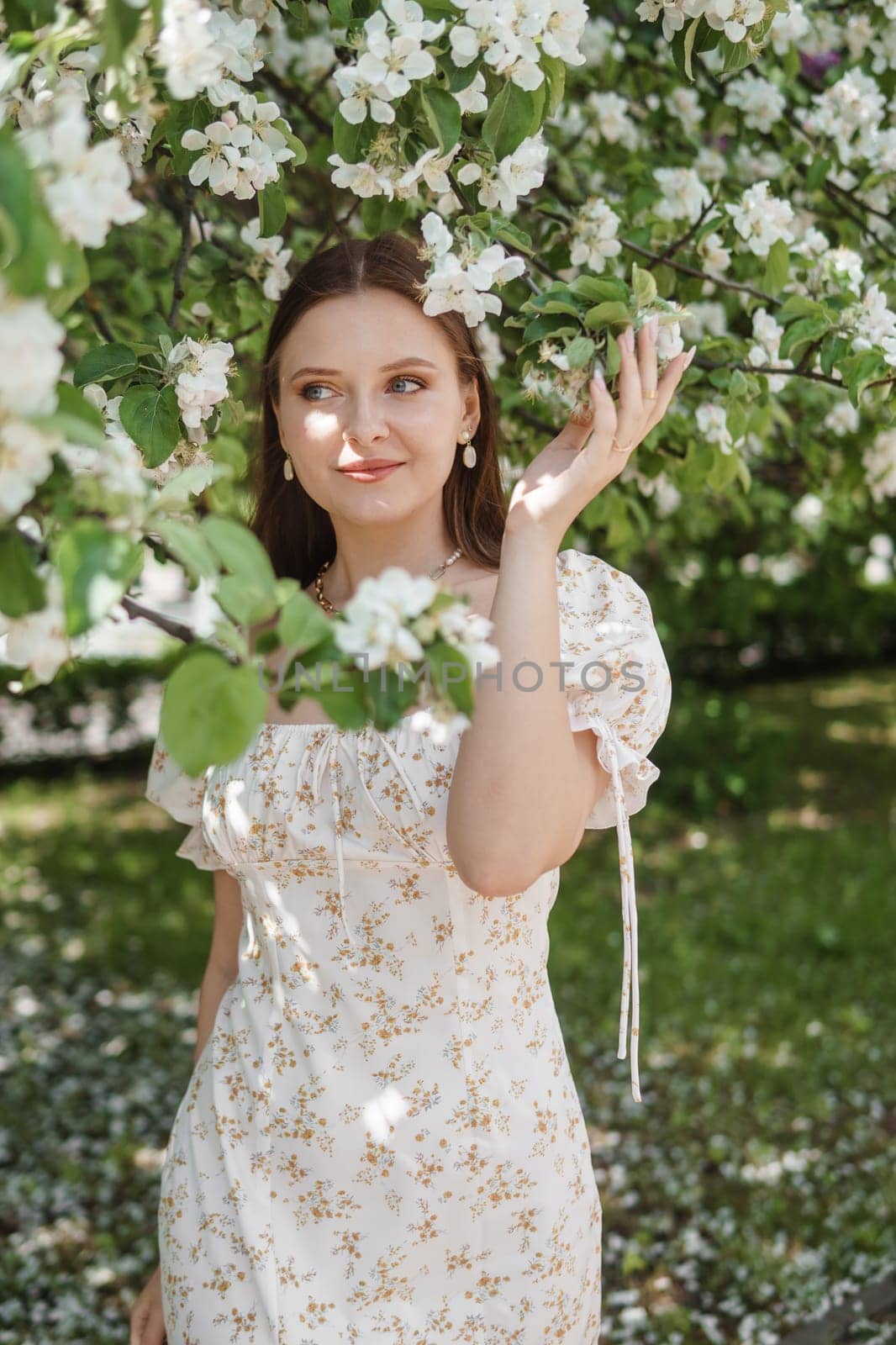 An attractive long-haired woman walks in the spring in the park of blooming apple trees. by Annu1tochka