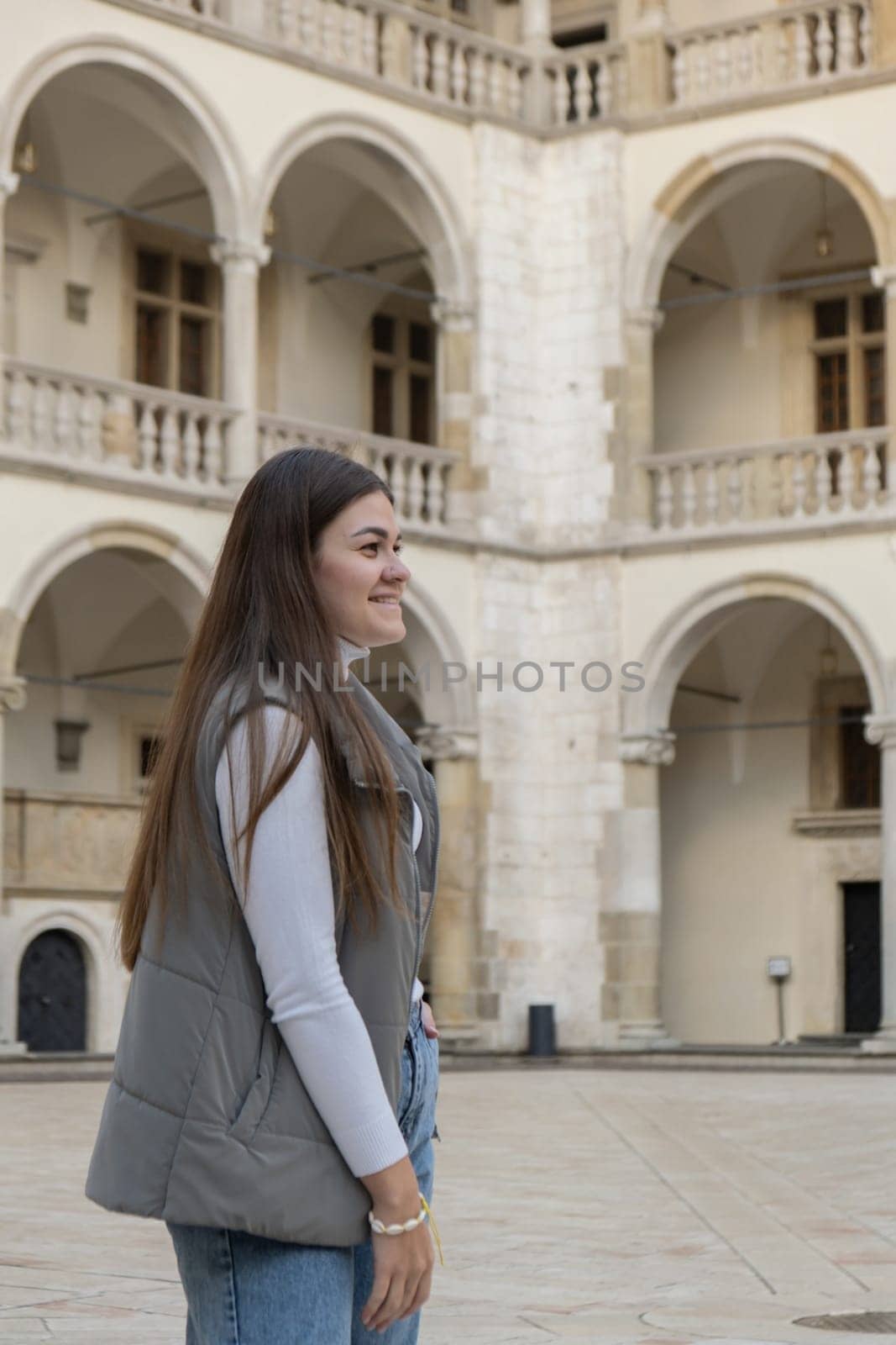 Female traveler in historical places looks around courtyard of landmark in Krakow Wawel castle. Tourist in historic place on sunny day. woman Tourism and blogging sharing live online for audience travel together