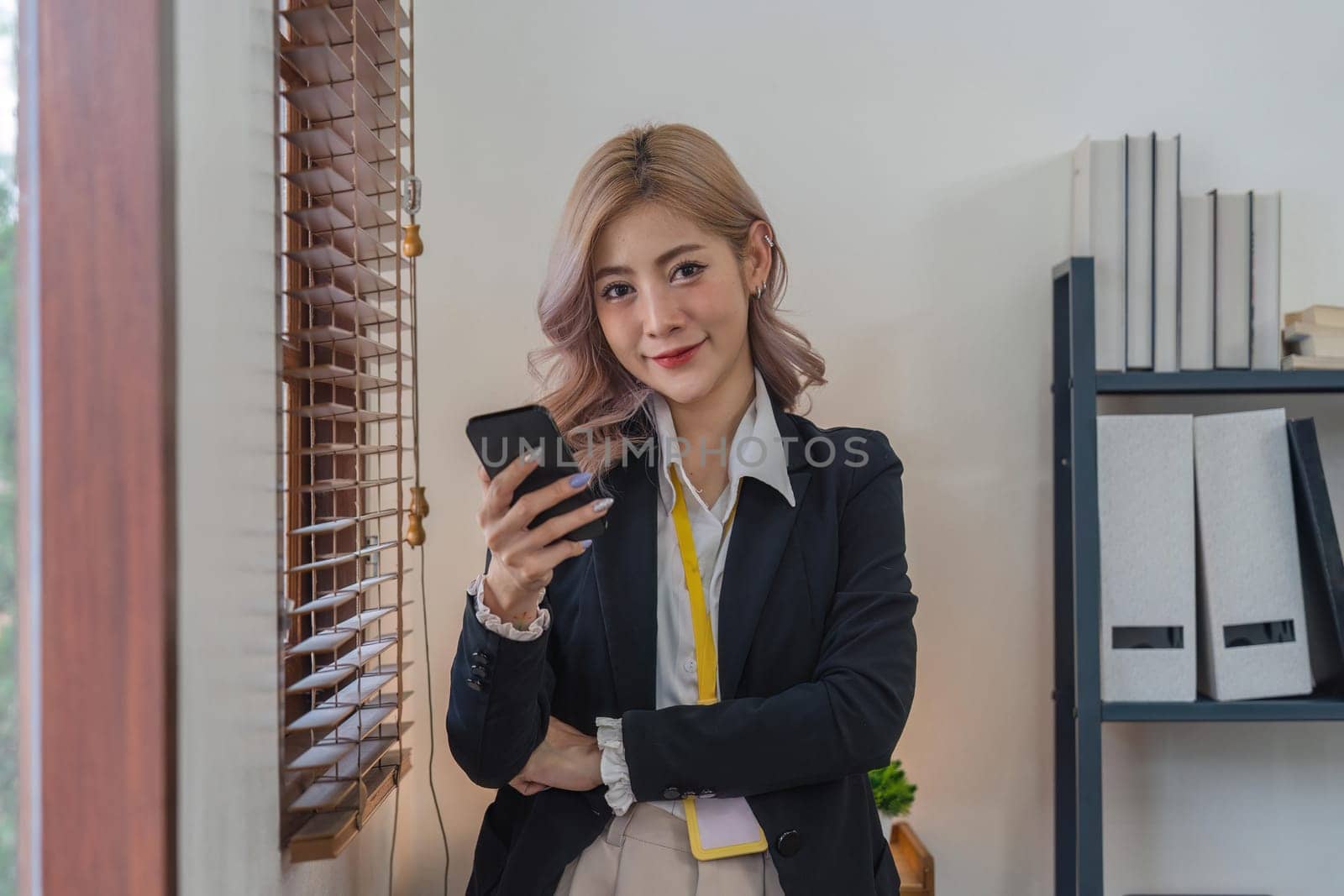 Smiling businesswoman using phone in office. business entrepreneur looking at her mobile phone and smiling by nateemee