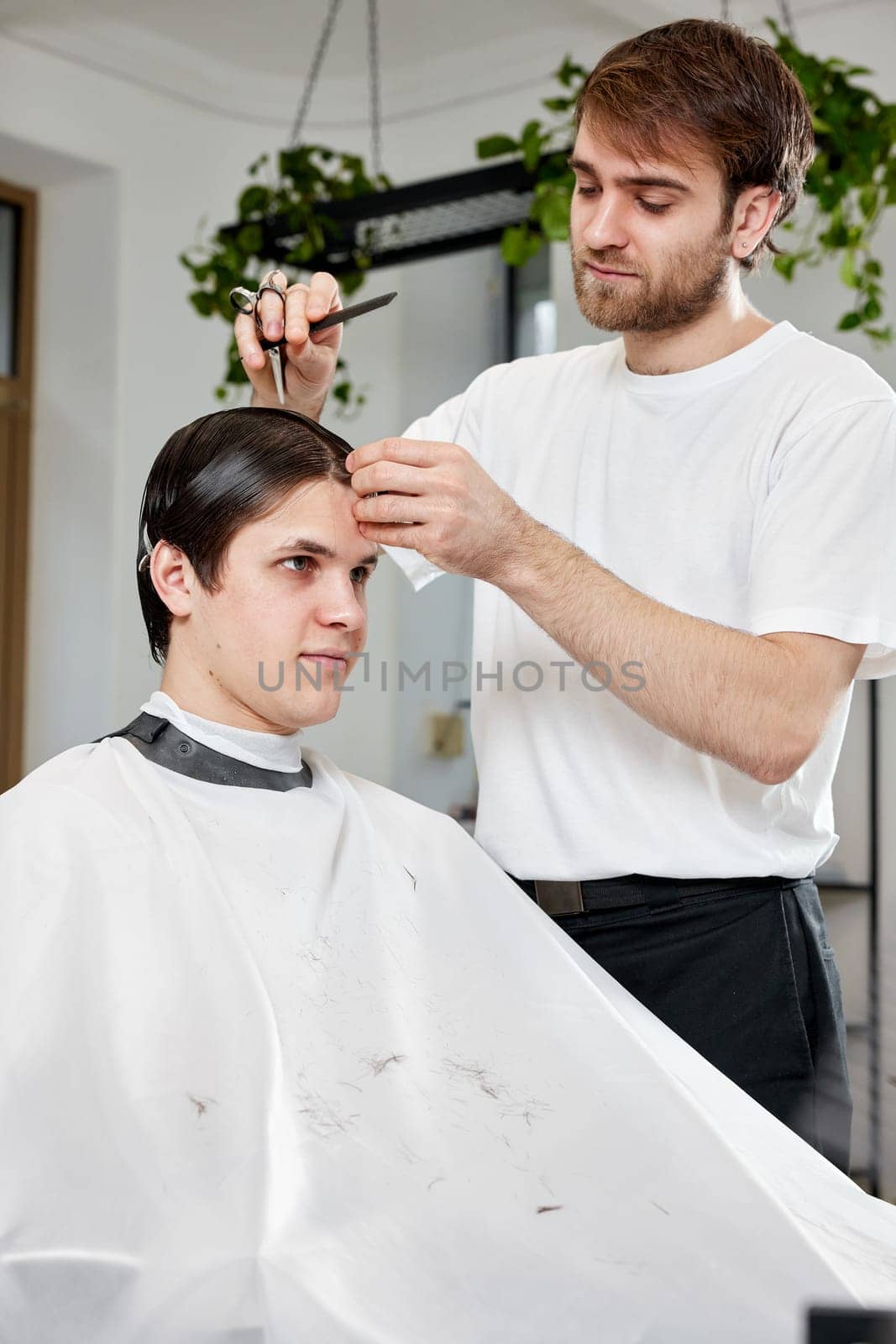 handsome young man visiting professional hairstylist in barber shop