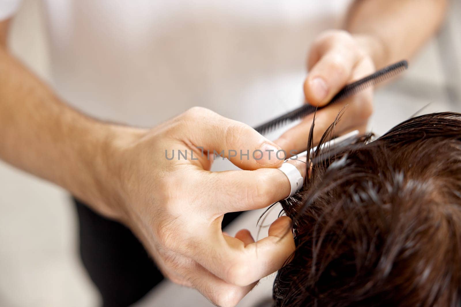 hairdresser does haircut for caucasian man in barber shop. close-up