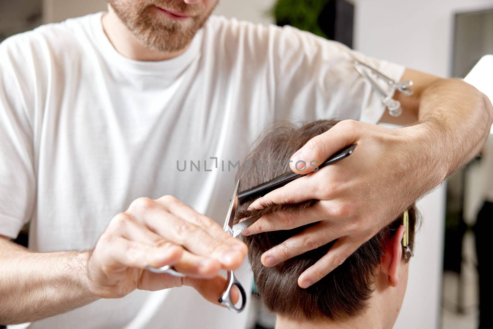 hairdresser does haircut for caucasian man in barber shop. close-up
