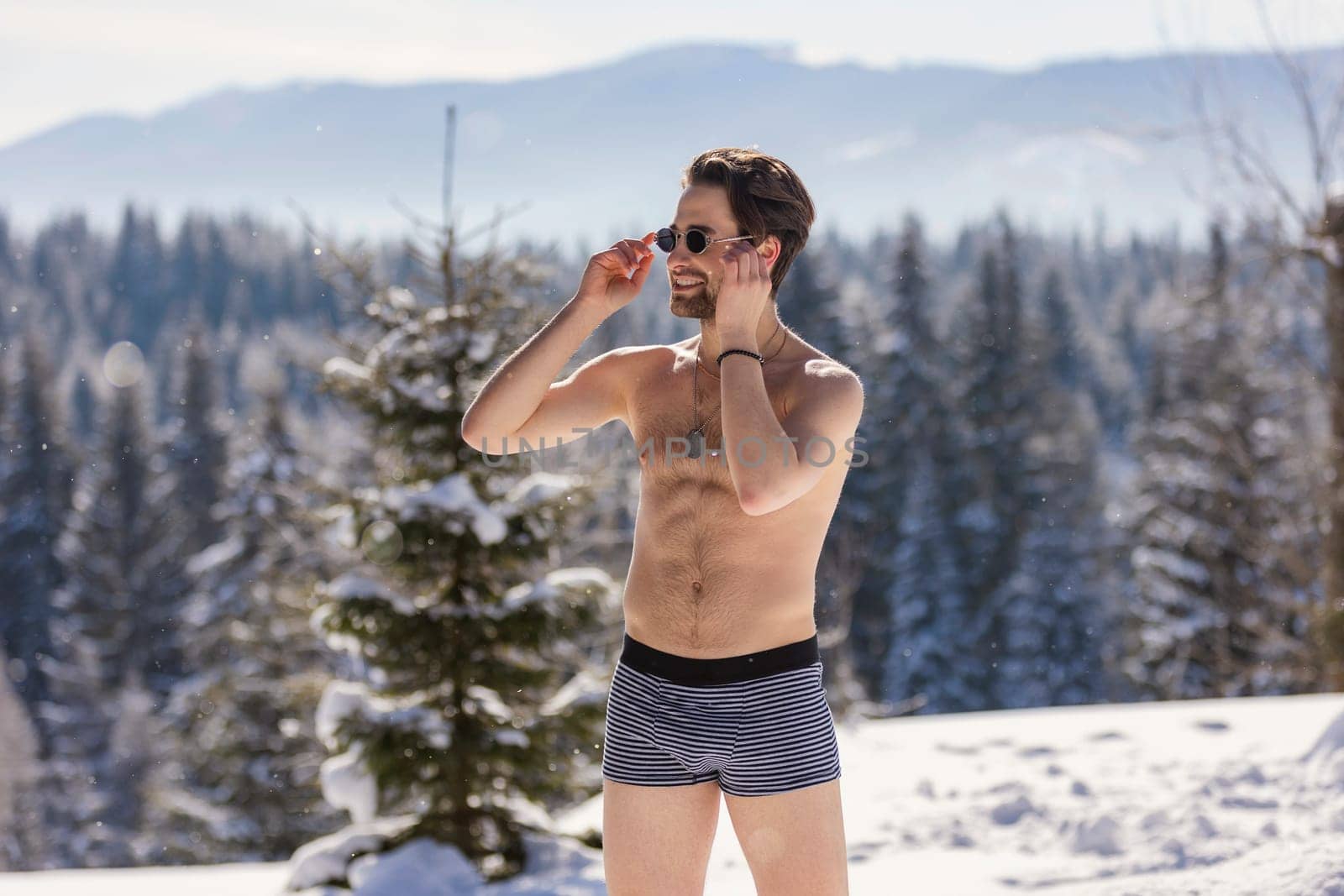 man in shorts and sunglasses on the background of snow-capped mountains