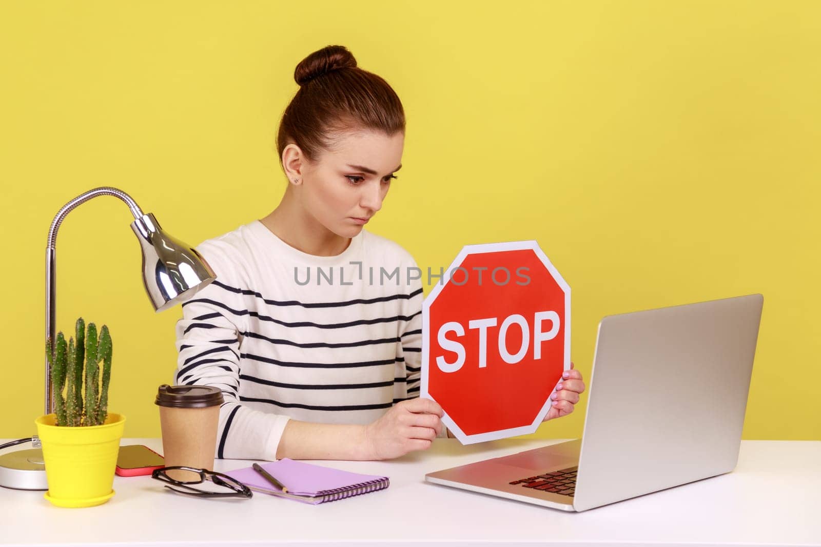 Woman manager wearing striped shirt showing stop red sign to laptop screen, avoiding conflicts. by Khosro1