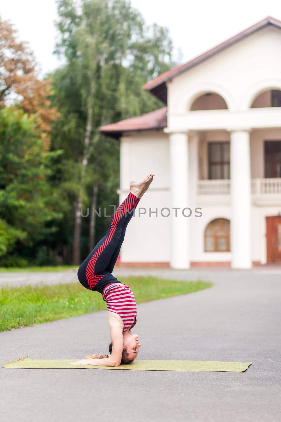 Sporty woman practicing yoga, doing headstand exercise, salamba sirsasana pose, working out outdoor. by Khosro1