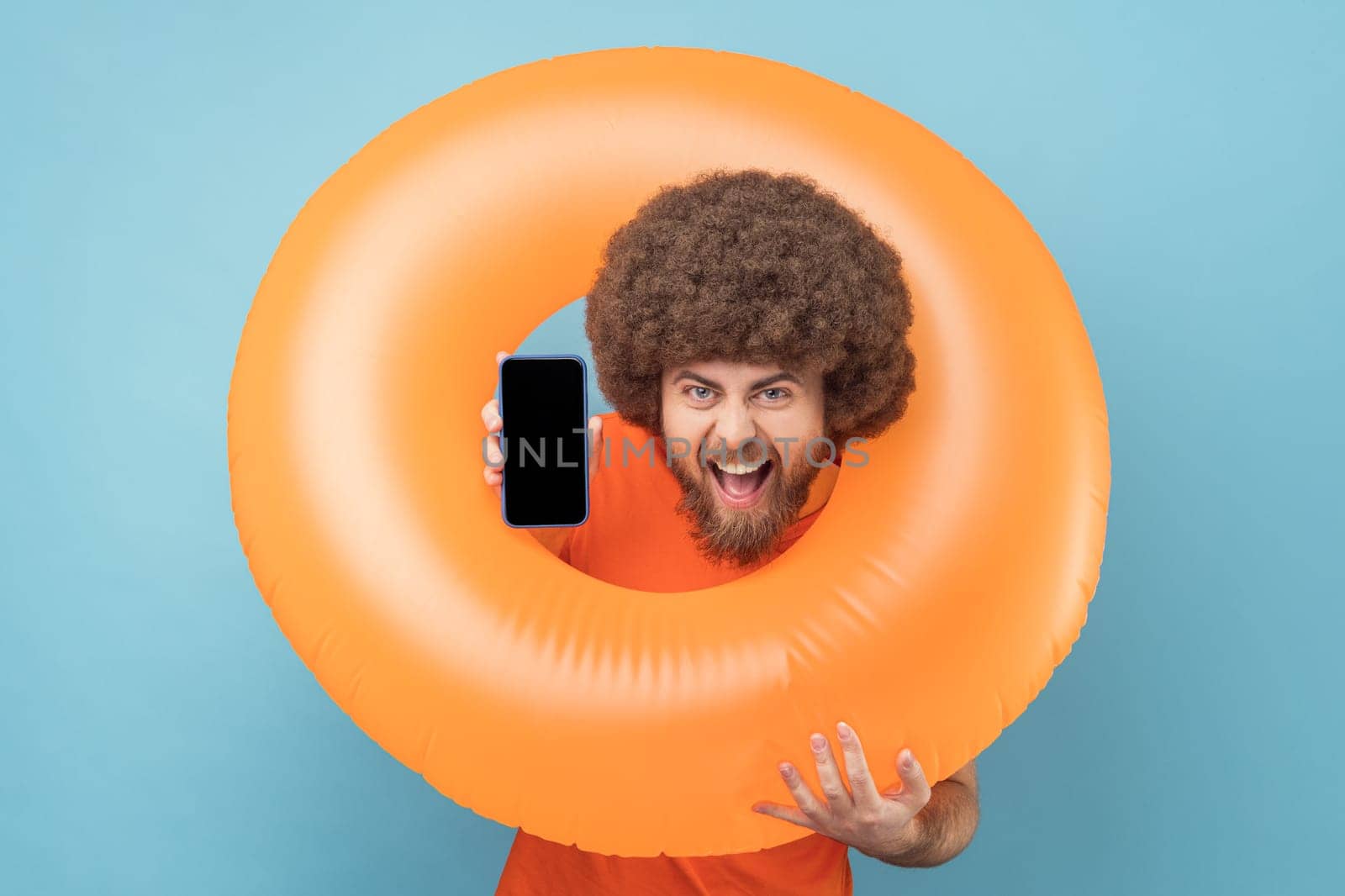 Man holding orange rubber ring, showing phone with blank screen for advertisement. by Khosro1