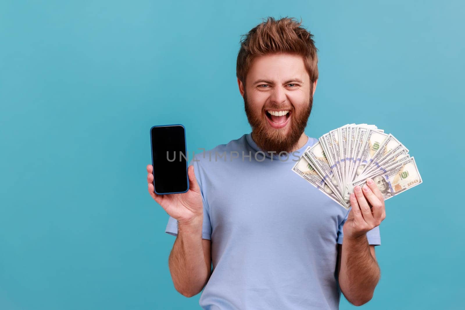 Man in T-shirt holding dollar banknotes and cell phone with empty screen, online betting, winning. by Khosro1