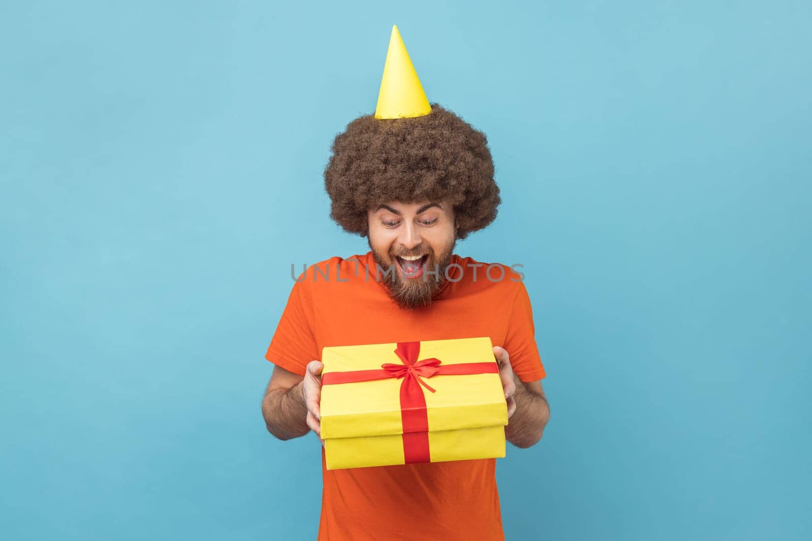 Man holding gift and looking at camera with toothy smile, gifts and bonuses, celebration. by Khosro1