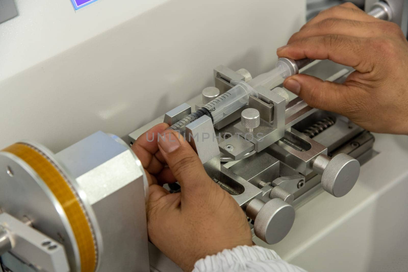 A closeup shot of hands working on a machine in a medical production warehouse for syringes
