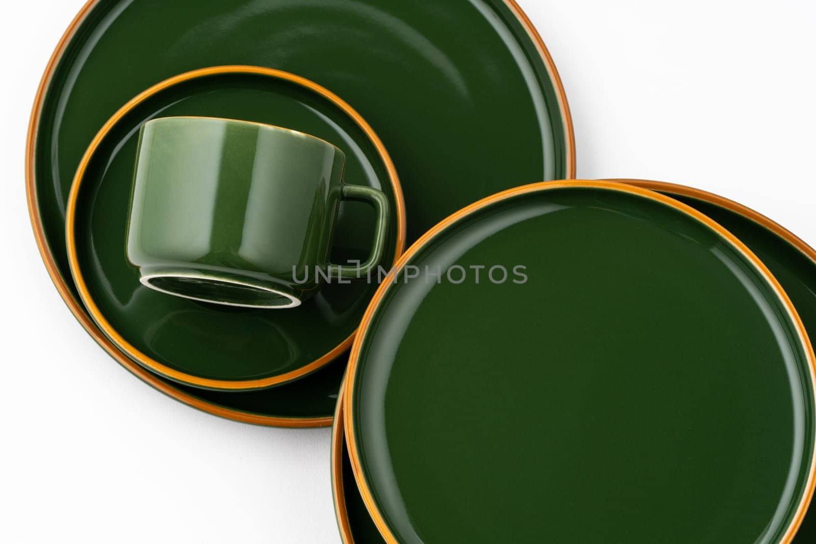 A set of dark green ceramic tableware with orange outlines on a white background