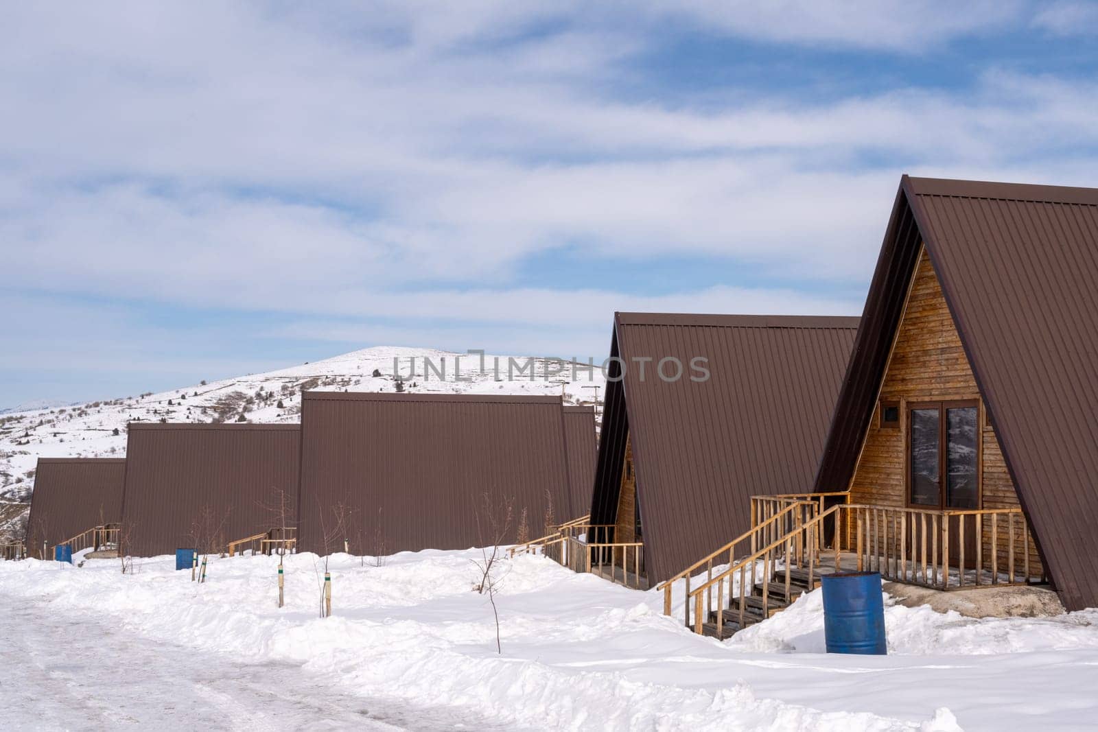 The wooden cottages surrounded by snow. A recreation area in the mountains