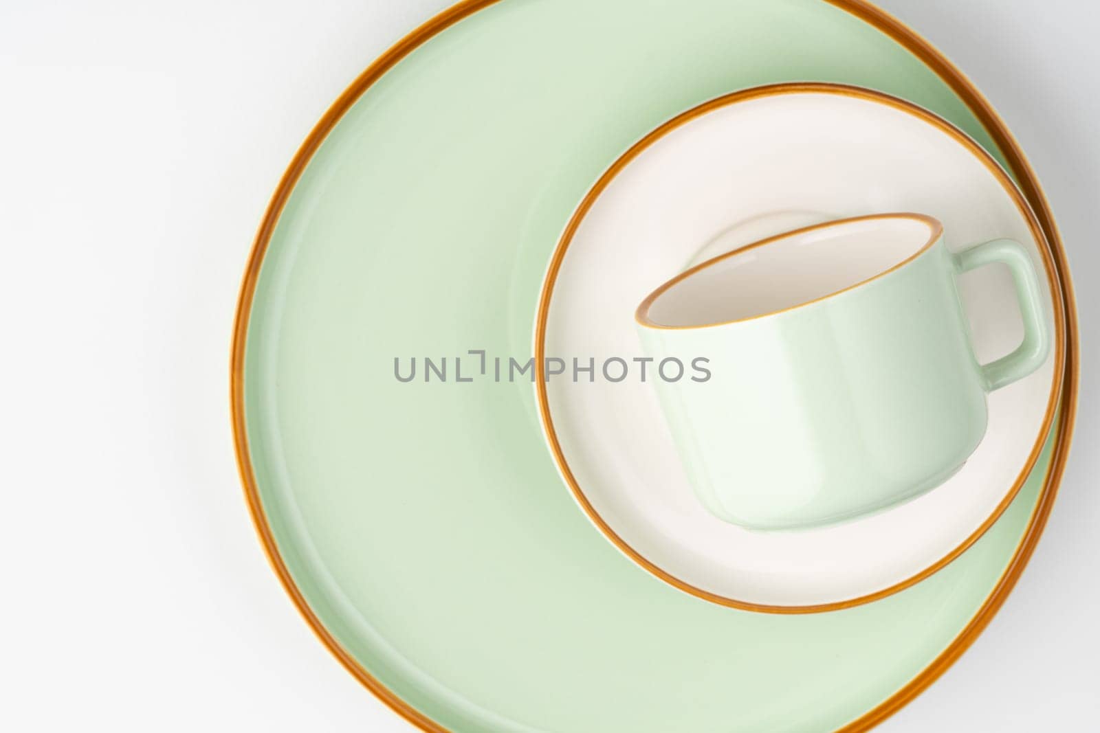 A set of white and pastel green ceramic tableware with orange outlines