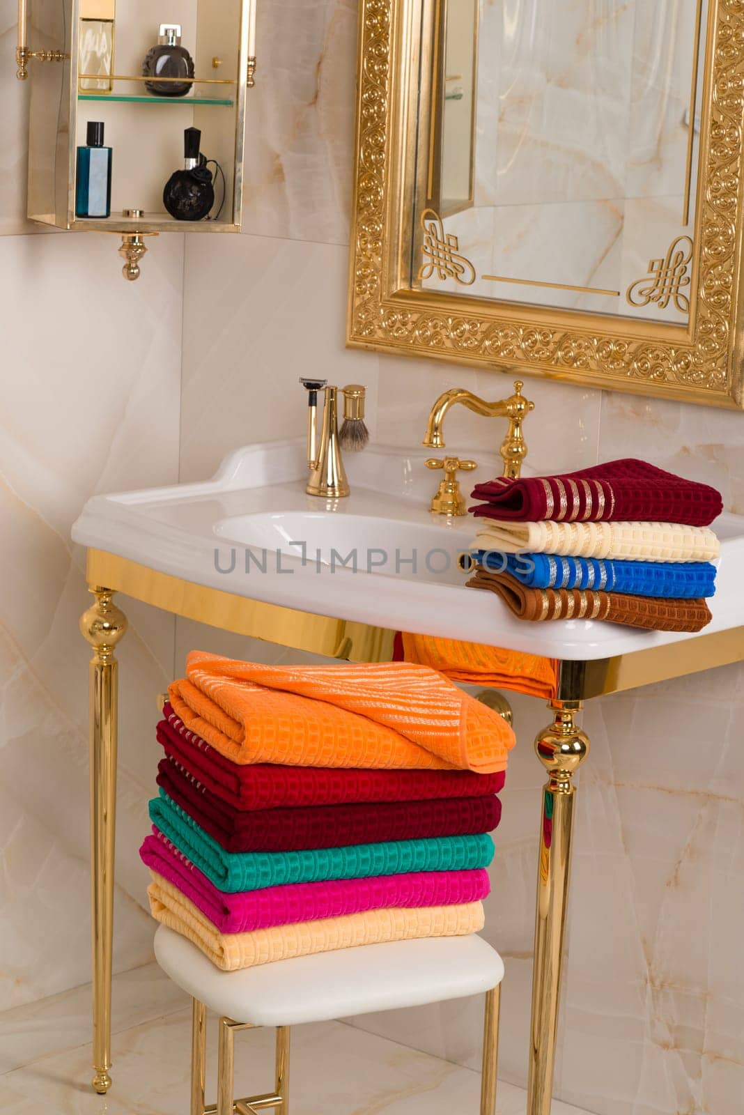 A vertical shot of folded colorful bamboo towels in a beautiful vintage golden bathroom interior