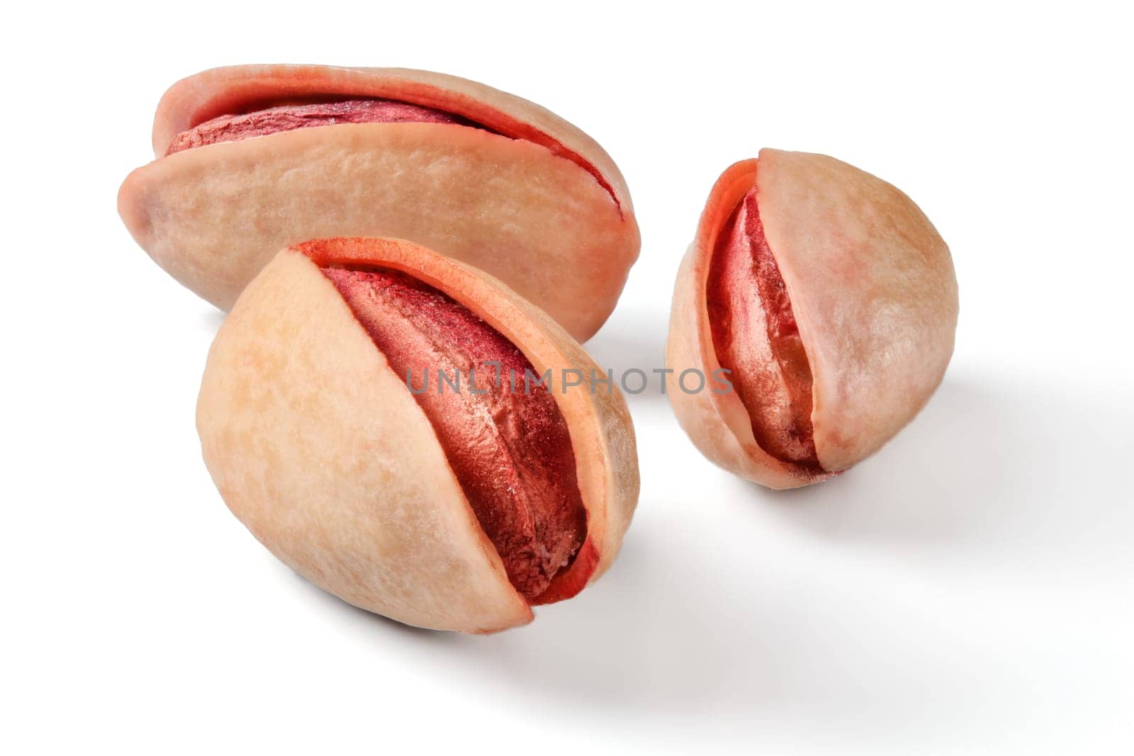 Three roasted, salted, red turkish pistachios isolated on white background.