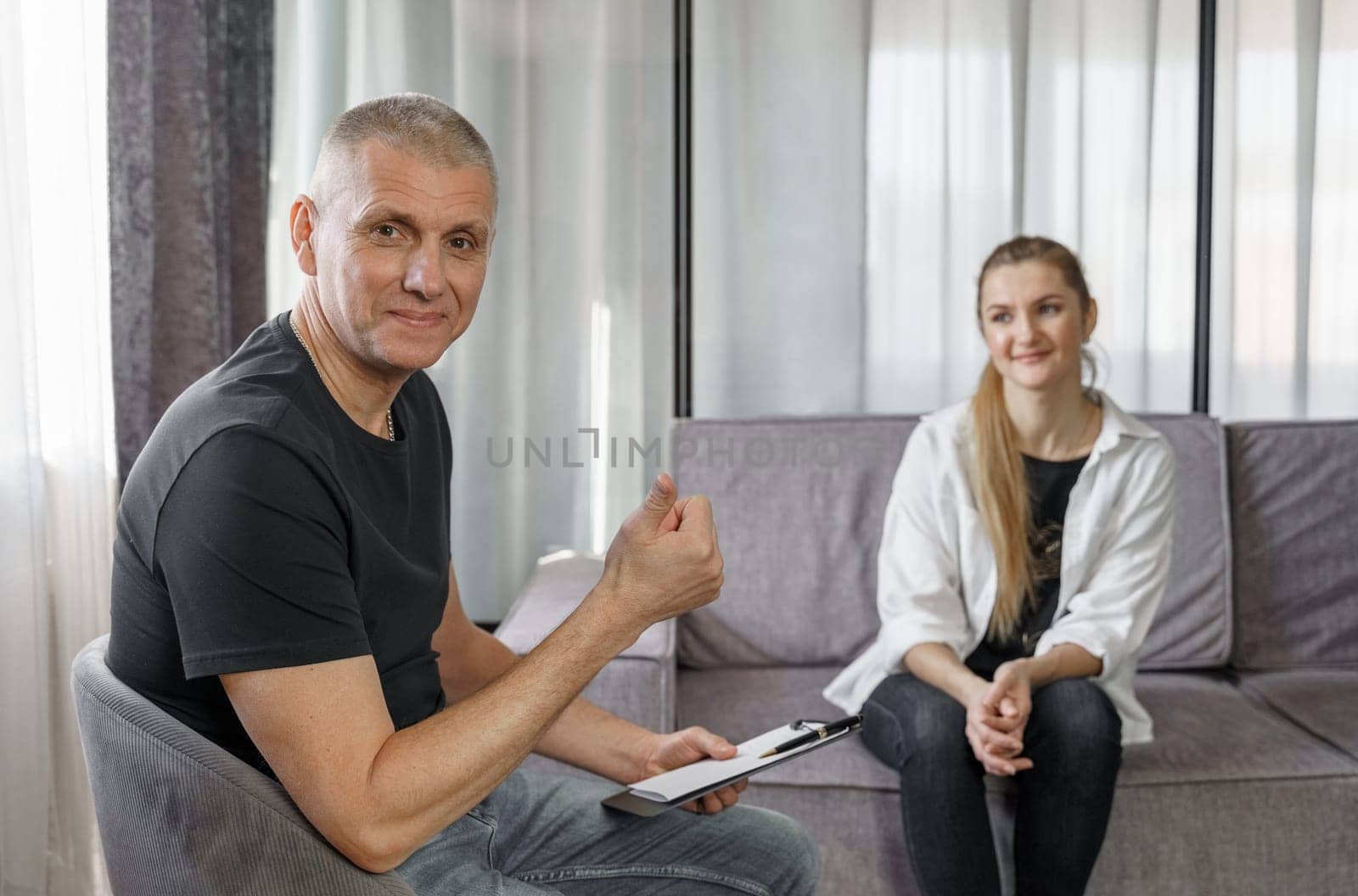 A male psychologist conducts a consultation, as a result of which the female client is satisfied with the result. He shows a hand gesture - class, excellent.