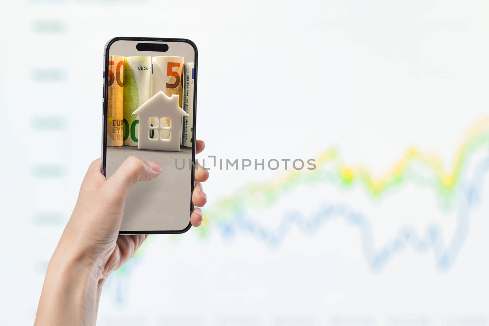 Phone in hand against the background of investment chart, investment concept, broker services, real estate value, economic growth, dividend payout, copy space.