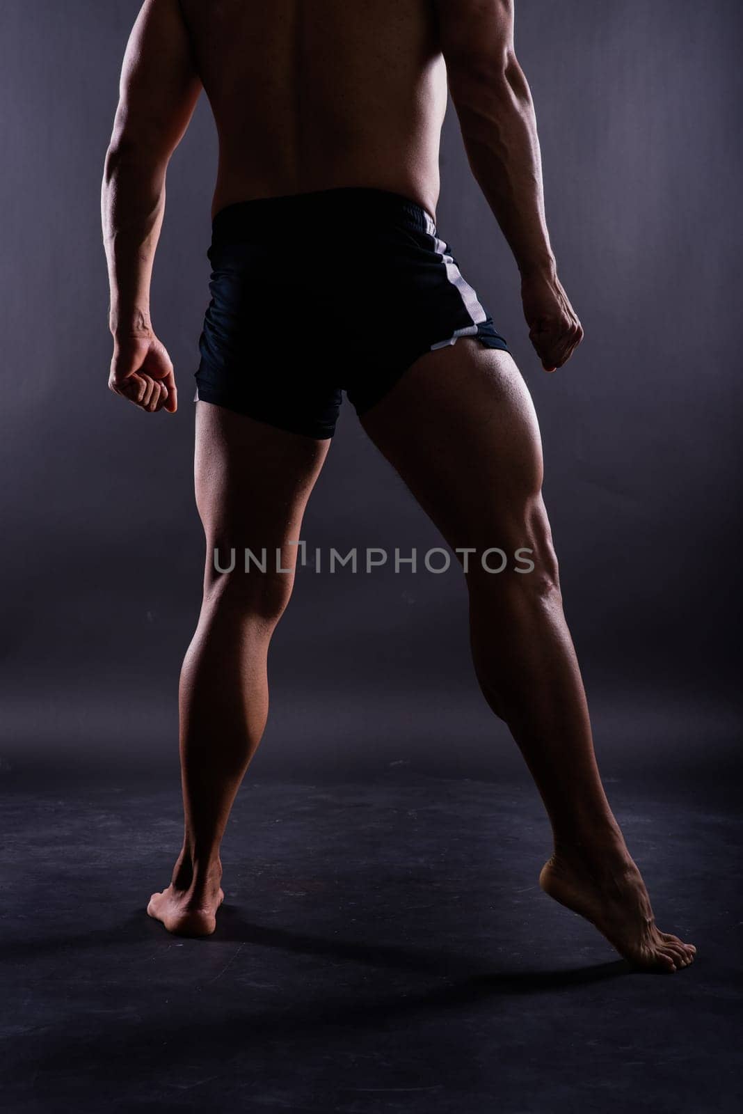 Muscular male legs close up studio shot dark background by Zelenin