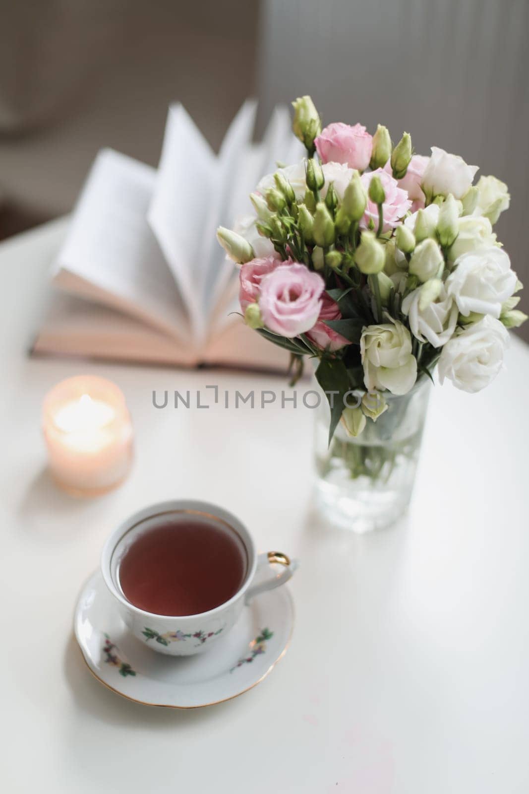 Romantic Spring still life. Romantic background with cup of tea, rose flowers and open book over white table